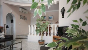 A living room with a sofa, a coffee table, a potted plant, and a TV stand.