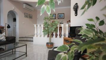 A living room with a sofa, a coffee table, a potted plant, and a TV stand.