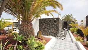A pathway leading to a building with a stone wall and a bicycle parked by the entrance.