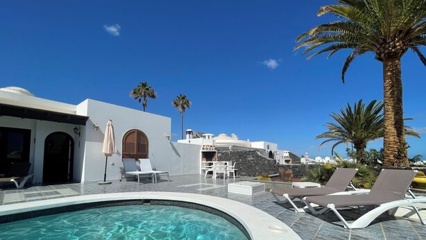 A pool area with lounge chairs and a stone wall.