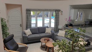 A living room with a sofa, a coffee table, and a view of a pool.