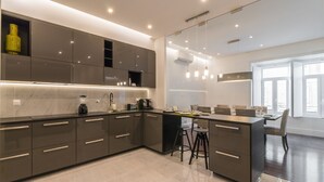 A modern kitchen with a central island, built-in appliances, and a dining area with a large window. - House Sweet Home - Lisbon Center (Lisboa)