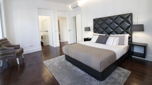 A modern bedroom with a large bed, a nightstand, a chair, and a walk-in closet. - House Sweet Home - Lisbon Center (Lisboa)