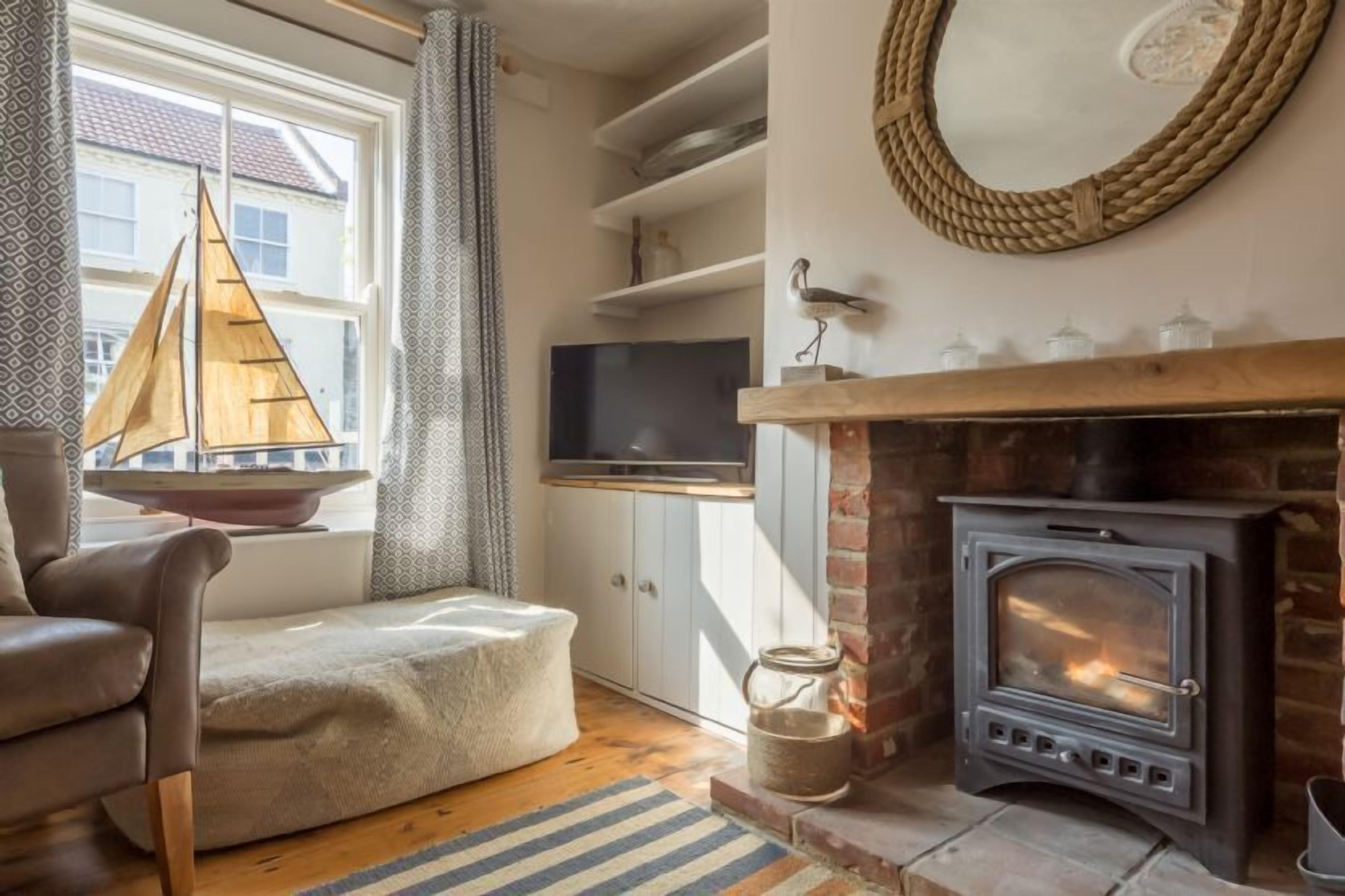 Un salon chaleureux avec une cheminée, un téléviseur et une décoration sur le thème de la voile.