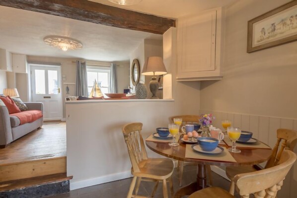 A dining area with a wooden table set for breakfast, surrounded by wooden chairs. - Burnham Cottage, Wells-next-the-Sea, Norfolk (Wells-next-the-Sea)