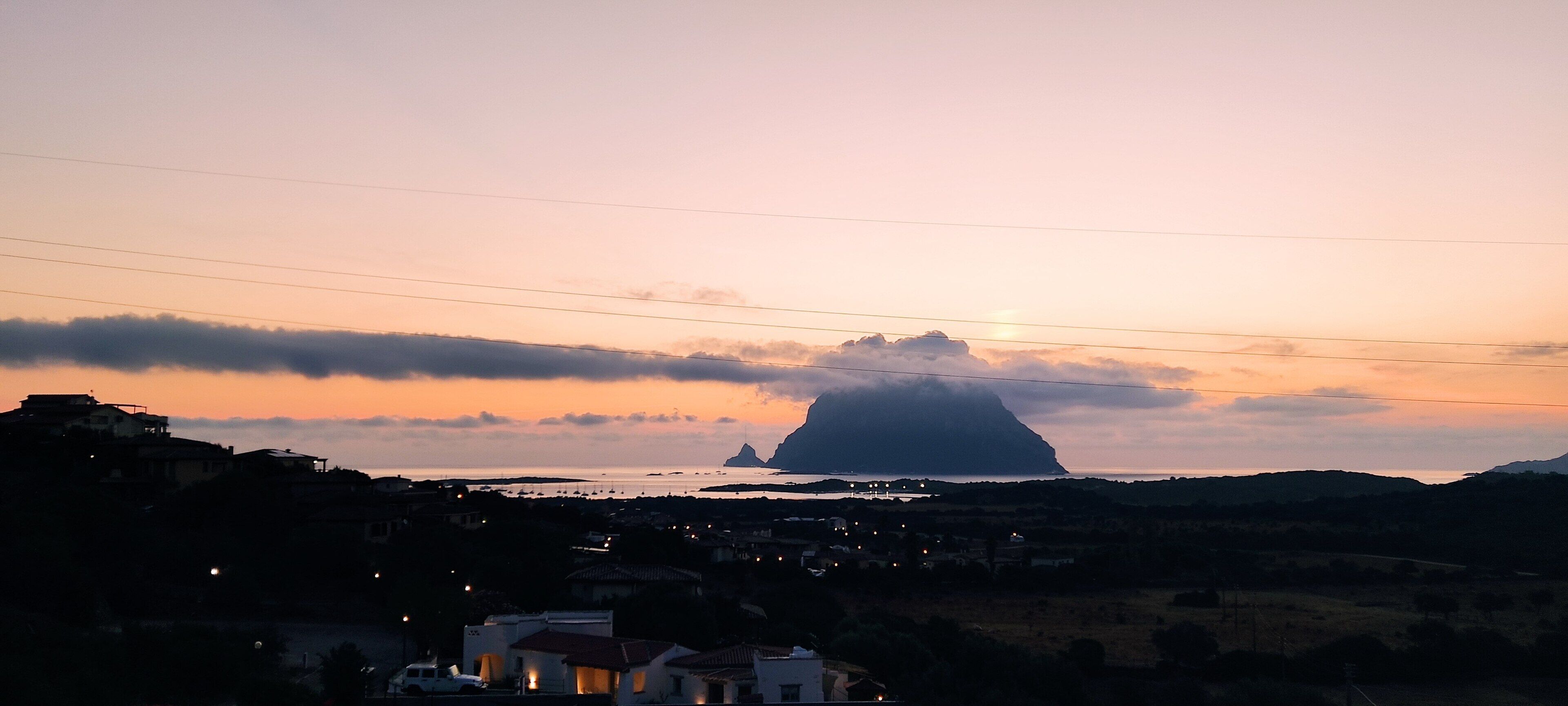 Un pueblo costero al atardecer con una montaña imponente al fondo.