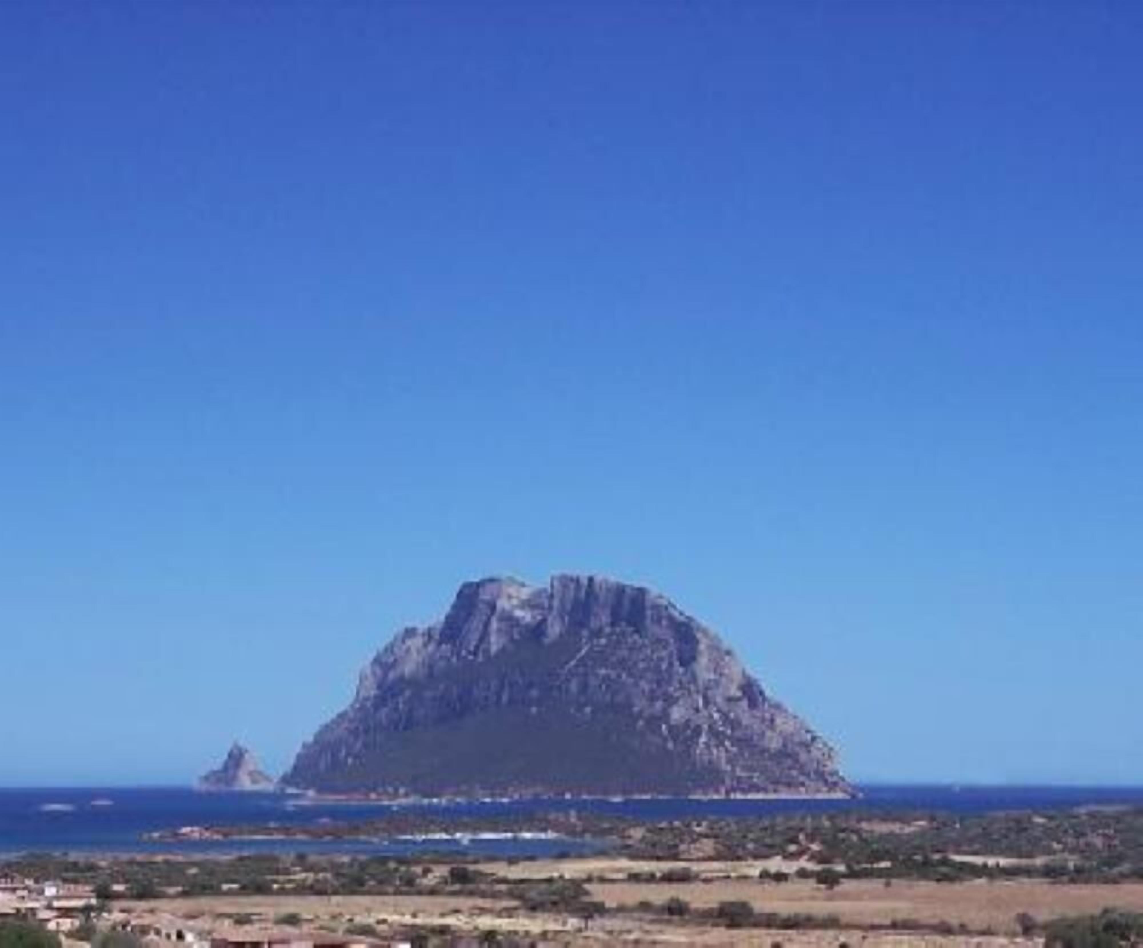 Une montagne d’où l’on a une vue dégagée sur la côte et sur une petite île au loin.