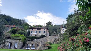 A stone building with a stone staircase, a grassy lawn, and pink flowers.
