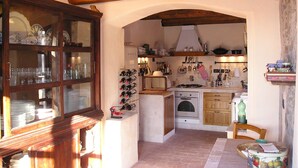 A rustic kitchen with wooden beams, a wine rack, and a stove.