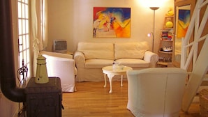 A living room with a sofa, a small table, a lamp, a bookshelf, and a painting on the wall.