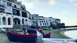 Botes en una playa arenosa con edificios al fondo.