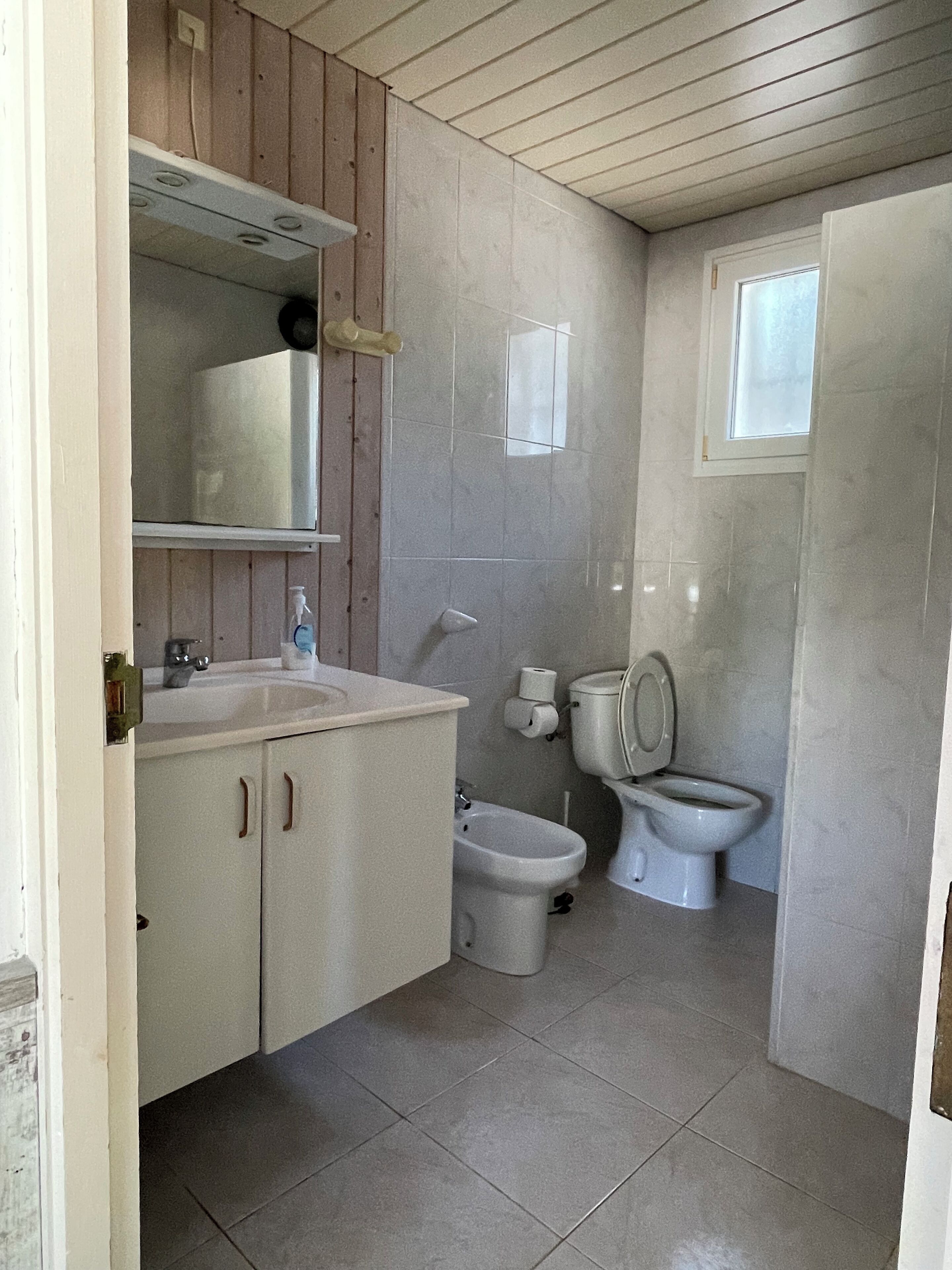 Ein kleines Badezimmer mit Waschbecken, Toilette, Bidet und Spiegel.