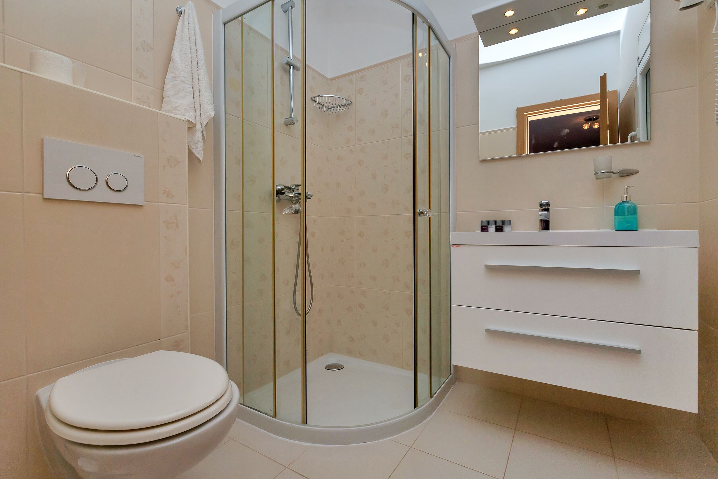 A modern bathroom with a glass-enclosed shower, a toilet, and a vanity with drawers.