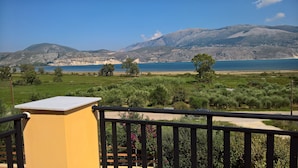Un balcón con vistas a un paisaje costero, que incluye una masa de agua y montañas a lo lejos.