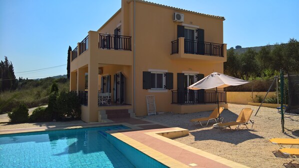A two-story building with a swimming pool, outdoor seating, and a balcony.