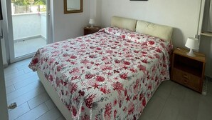 Een slaapkamer met een bed, nachtkastjes, een spiegel en een lijst met een afbeelding aan de muur.