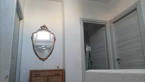 Een badkamer met een houten kast, een spiegel en een douchehoek.