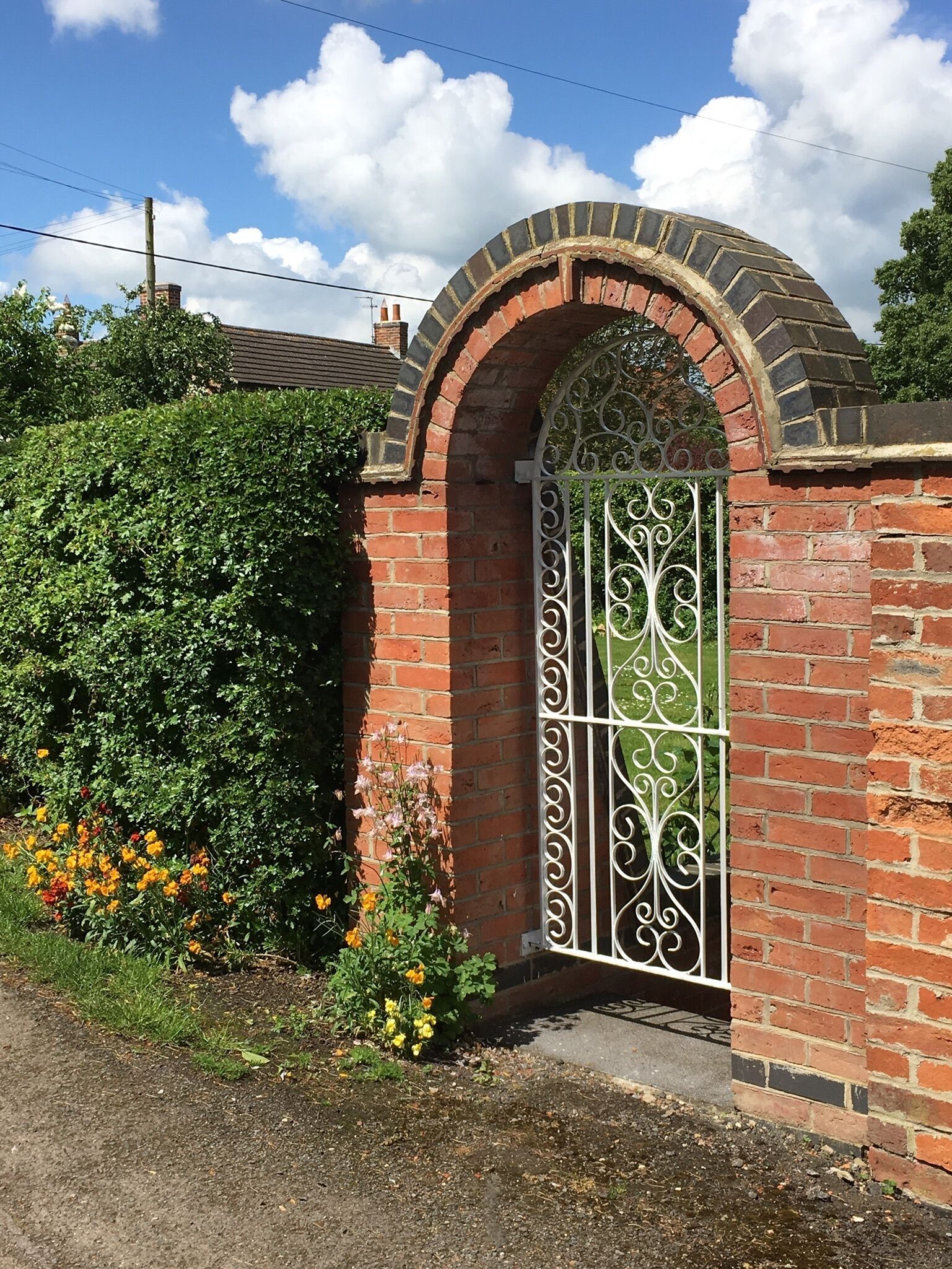 A brick gate with an arched top and decorative metal bars.
