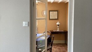 Un couloir avec une porte donnant sur une pièce où se trouvent un lit, un bureau et une chaise.