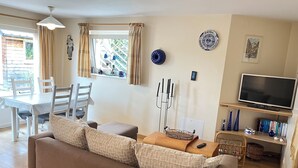 A living room with a sofa, a dining table with chairs, a TV, and a window with curtains. - Apartment/ flat - Wettolsheim (Wettolsheim)