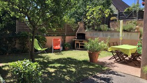 A backyard with a barbecue area, a green chair, a table with a yellow tablecloth, and a potted plant. - Apartment/ flat - Wettolsheim (Wettolsheim)