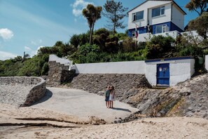 Un edificio costero con una escalera de piedra, una puerta azul y una bandera.