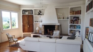 A living room with a white sofa, wooden cabinet, bookshelves, and a fireplace.