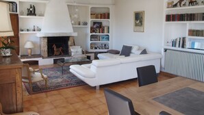 A living room with a fireplace, white sofas, a coffee table, and a bookshelf.