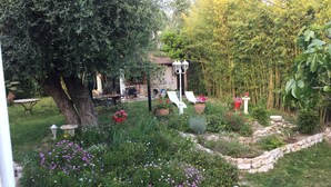 A garden with a stone border, a tree, and outdoor furniture.