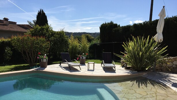 A swimming pool with lounge chairs and potted plants.