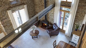 A stone-walled room with a fireplace, a leather sofa, a dining table, and a staircase.