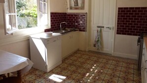 Una cocina con ventana, un lavabo, un refrigerador y una puerta con una toalla colgada.
