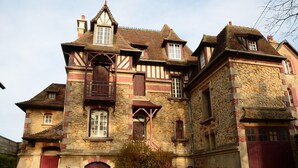 Un edificio grande e histórico con múltiples ventanas, una entrada destacada y estructura de piedra y madera.