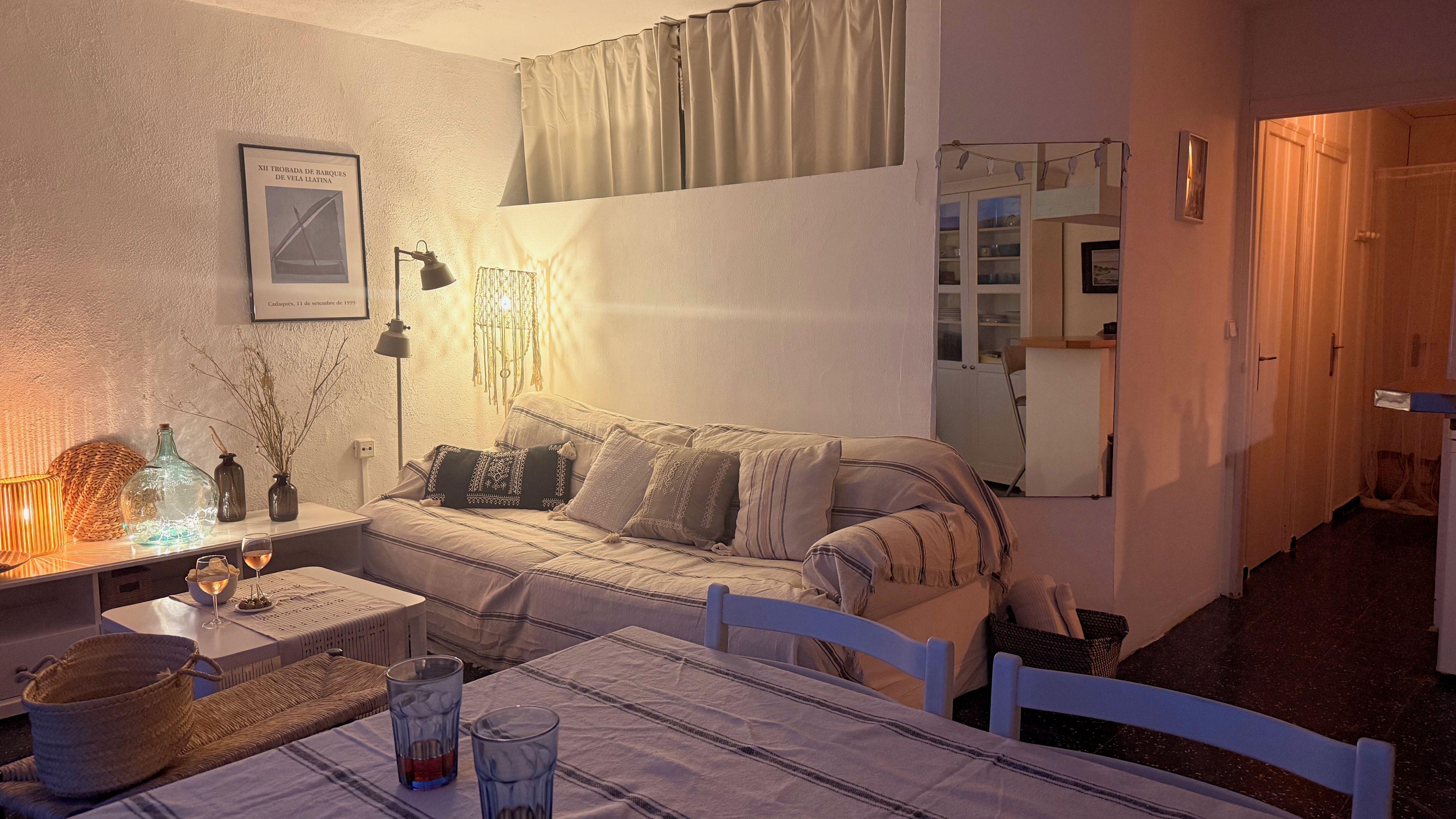 A cozy room with a bed, a table with glasses, a lamp, and a wall-mounted picture.