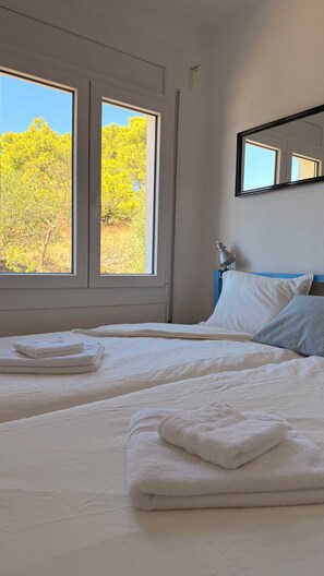 A hotel room with two beds, a large window, a bedside lamp, and a mirror on the wall. - INCREDIBLE VIEW (cadaques)