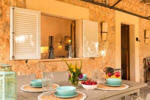 A dining table set with teal plates, clear glasses, and a bowl of fruit.