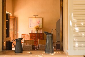 A room with a wooden cabinet, wicker chairs, and metal pitchers on a table.