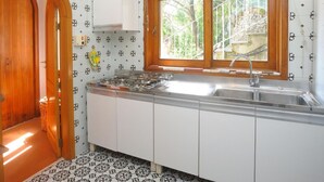 Cocina con estufa a gas, pileta y alacenas de madera.