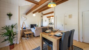 Una sala de estar acogedora con una mesa de madera para cuatro comensales, un sofá y un televisor al fondo.