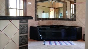 Un baño con una bañera negra, un espejo y baldosas estampadas en las paredes y el suelo.