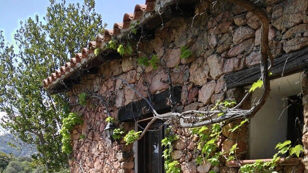 Un edificio de piedra con techo de tejas, una puerta y un pequeño porche.