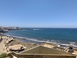 Une vue sur la côte, avec une plage, une jetée et un bâtiment doté d’un balcon donnant sur la mer.