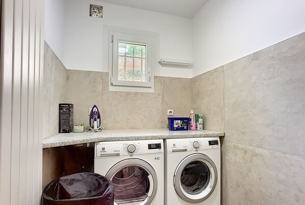 A compact laundry room with two front-loading washing machines, a small window, and a countertop with laundry supplies. - 220 m² villa with 4 suites, 4 bathrooms and stunning views of the Esterel (Fréjus)