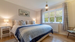 A bedroom with a bed, bedside table, lamp, window, and a chair. - Waterside, Wiveton, Norfolk (Wiveton)