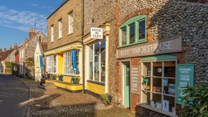 A traditional brick building with a sign reading "CLEY SMOKEHOUSE" and another sign indicating "MADE IN CLEY". - Waterside, Wiveton, Norfolk (Wiveton)