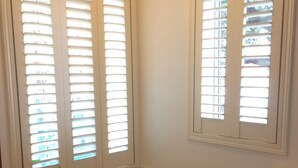 Une salle de bain avec une baignoire, des toilettes et des fenêtres équipées de stores.