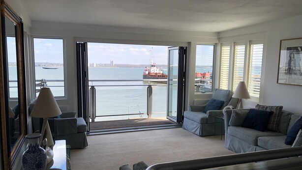 Un salon avec vue sur un port, comprenant un canapé, une table basse et une lampe.