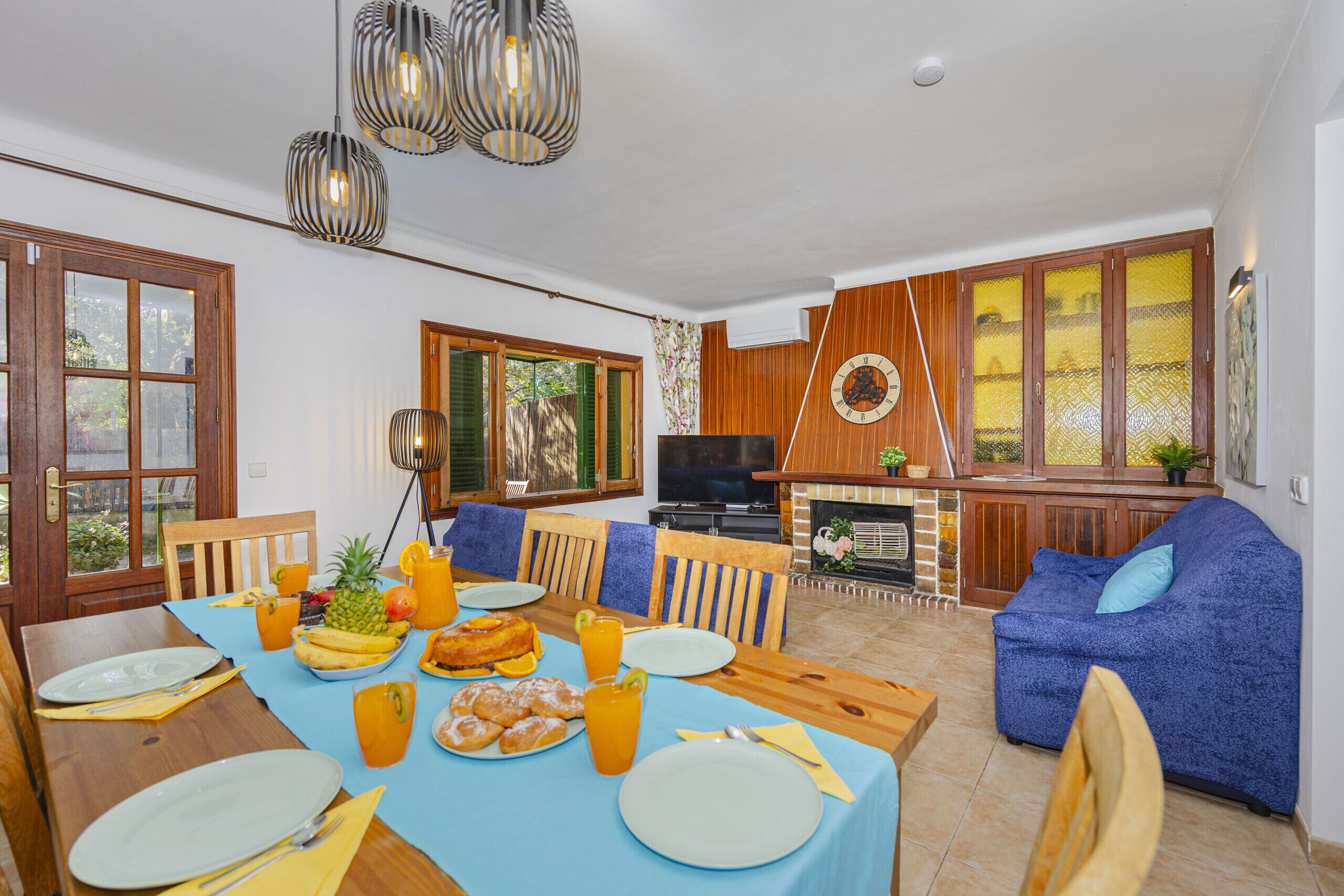 A dining area with a table set for breakfast, a TV, and a blue sofa.
