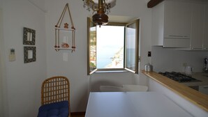 Una cocina con vista al mar, una silla de mimbre y una mesa de comedor.