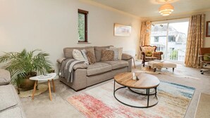 A living room with a sofa, coffee table, and a potted plant. - Windermere house with Lake View, 3 bed 3 bath, dog friendly with ample parking (Bowness-on-Windermere)